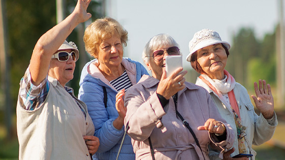 Ältere Frauen stehen im Freien und schauen lächelnd auf ein Smartphone