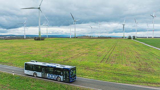 Ein blau-weißer Bus fährt über das Feld (Blick aus der Drohne)