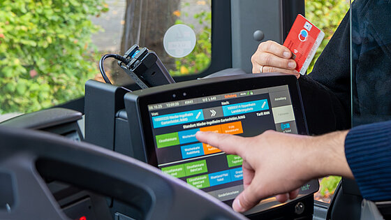 A bus driver serves a customer who pays with a debit card.