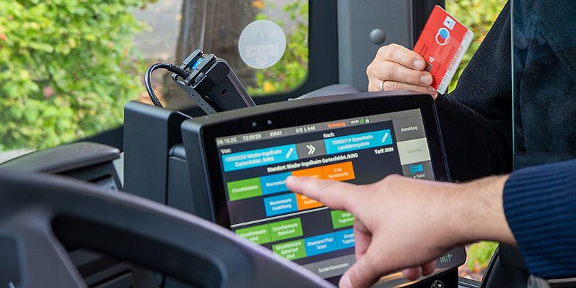 A bus driver serves a customer who pays with a debit card.