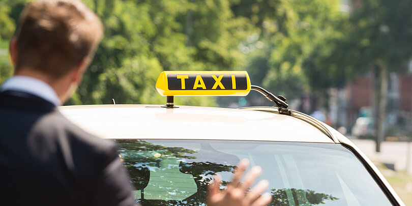 Ein Mann hält auf der Straße ein Taxi an