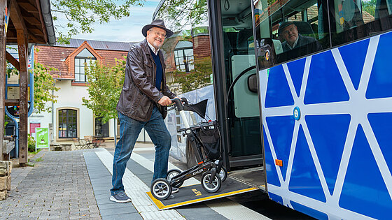 Älterer Mann steigt über die Rollstuhlrampe in den Bus ein