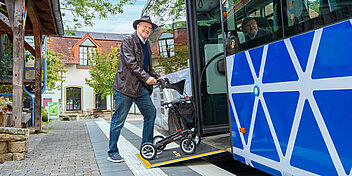 Älterer Mann steigt über die Rollstuhlrampe in den Bus ein