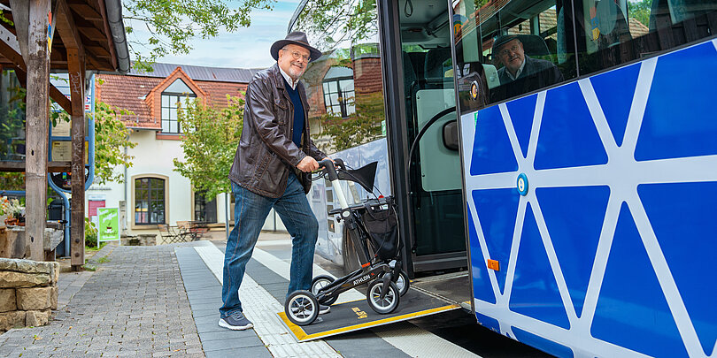 Älterer Mann steigt über die Rollstuhlrampe in den Bus ein