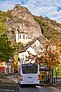 Ein blau-weißer Bus fährt auf der Straße vor der Hintergrund steht die Felsenkirche