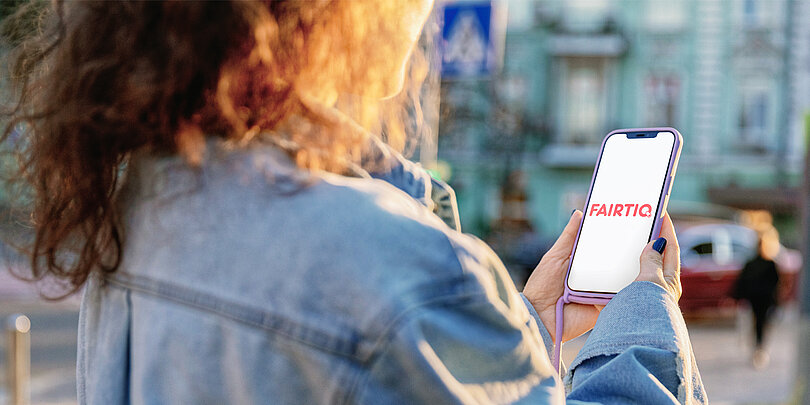 Eine Person hält ein Smartphone mit der "FAIRTIQ"-App