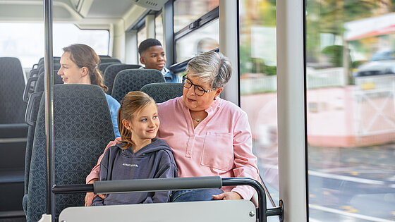 Eine Dame sitzt mit einem Mädchen im Bus