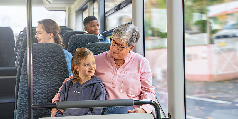 Eine Dame sitzt mit einem Mädchen im Bus
