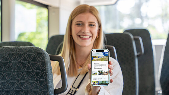Eine Frau zeigt RNN-Webseite auf Smartphone im Bus
