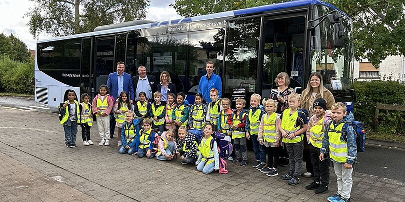 Eine Schulklasse steht vor einem Bus.
