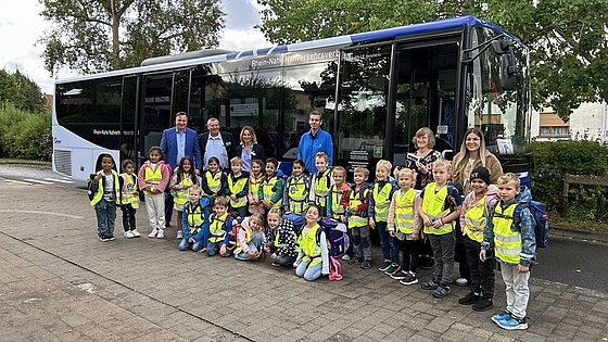 Eine Schulklasse steht vor einem Bus.