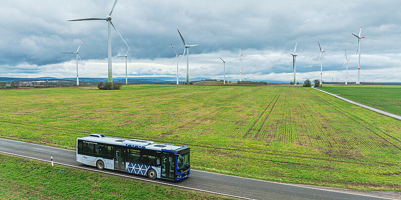 Ein blau-weißer Bus fährt über das Feld (Blick aus der Drohne)