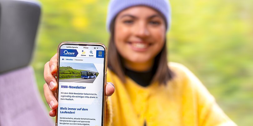 A woman shows the RNN website on her smartphone on the bus