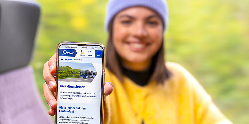 Eine Frau zeigt RNN-Webseite auf Smartphone im Bus